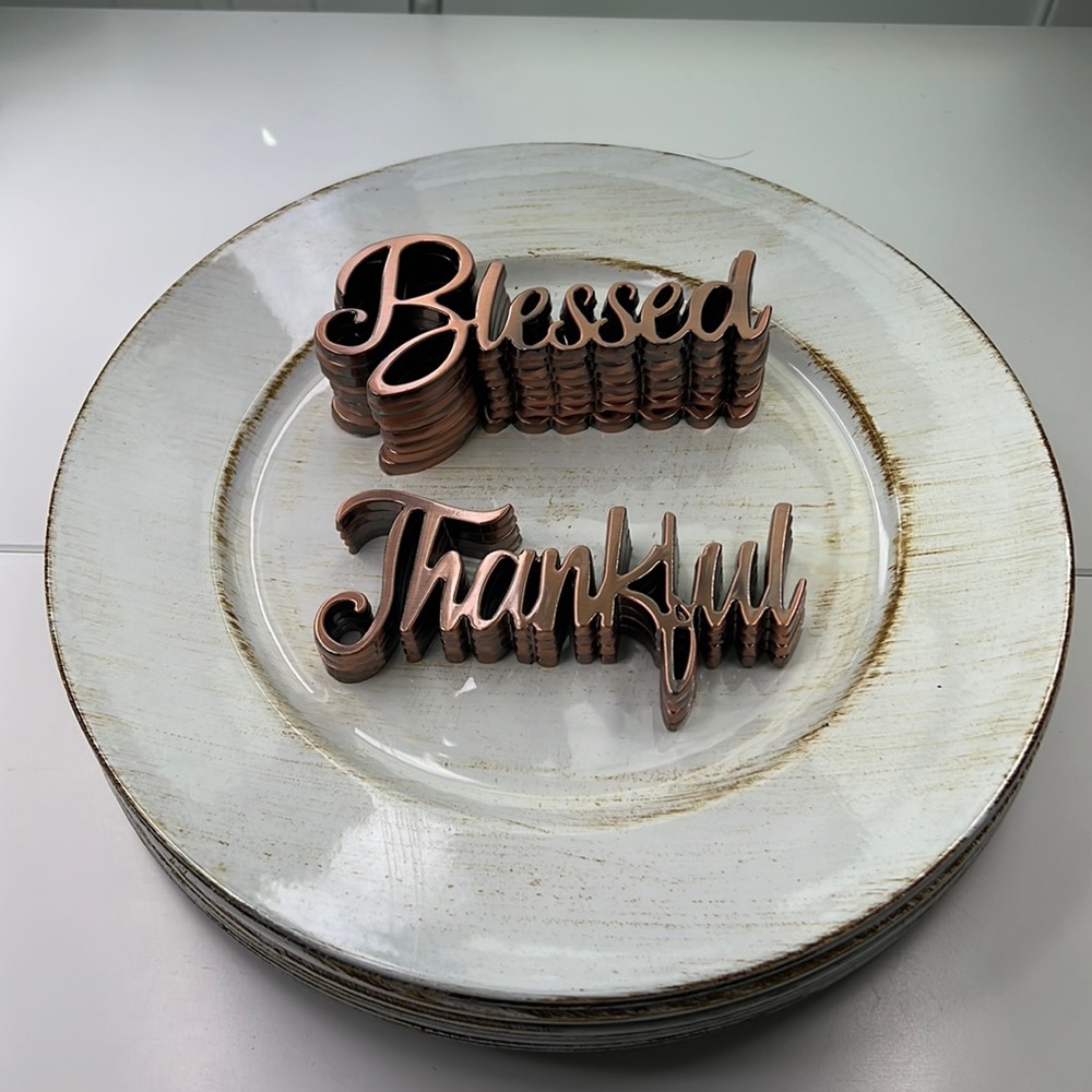 12 distressed, white chargers, and 12 stainless steel table setting ornaments